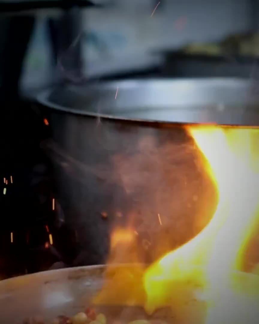 Flames rising from a flambe pan in a professional restaurant kitchen
