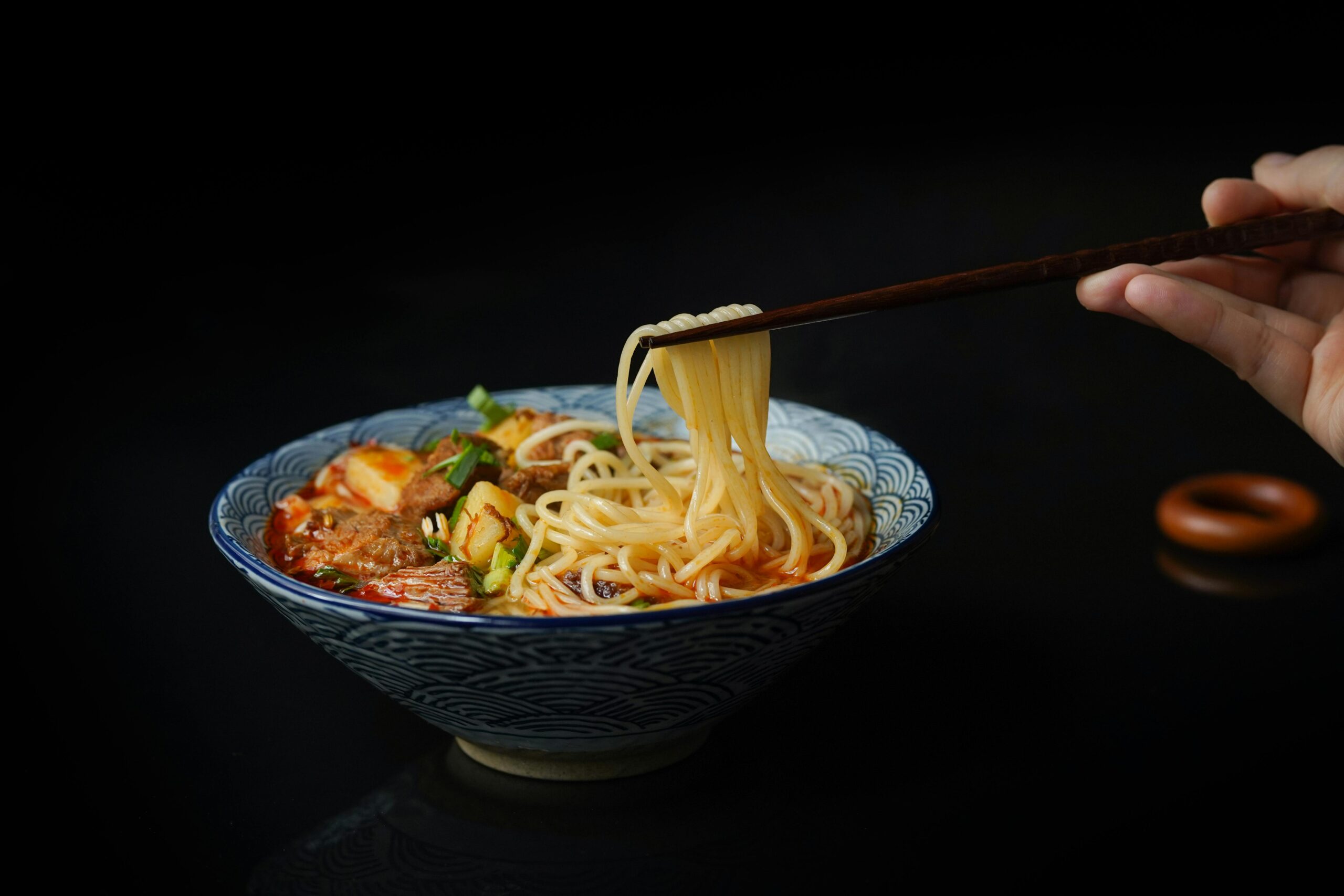 Mouth-watering Asian noodle soup with vegetables and meat, captured close up with chopsticks.