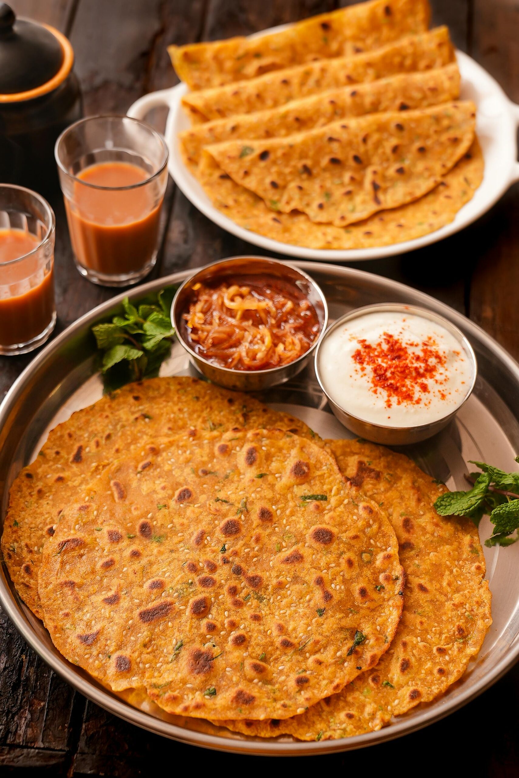 Indian paratha served with chutneys and masala chai, perfect for a hearty meal.