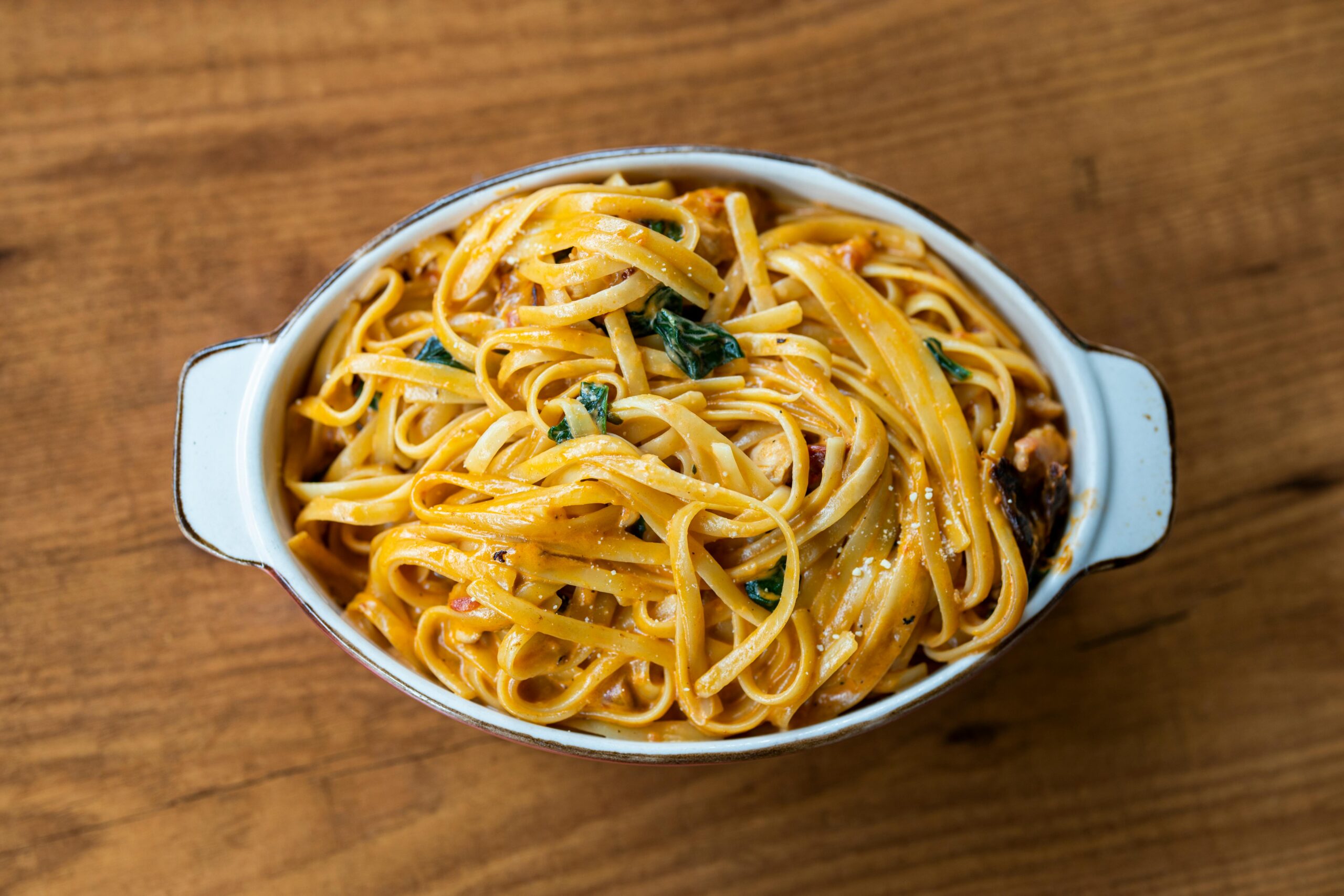 Top view of a creamy pasta dish with spinach in a white dish, perfect for dinner.