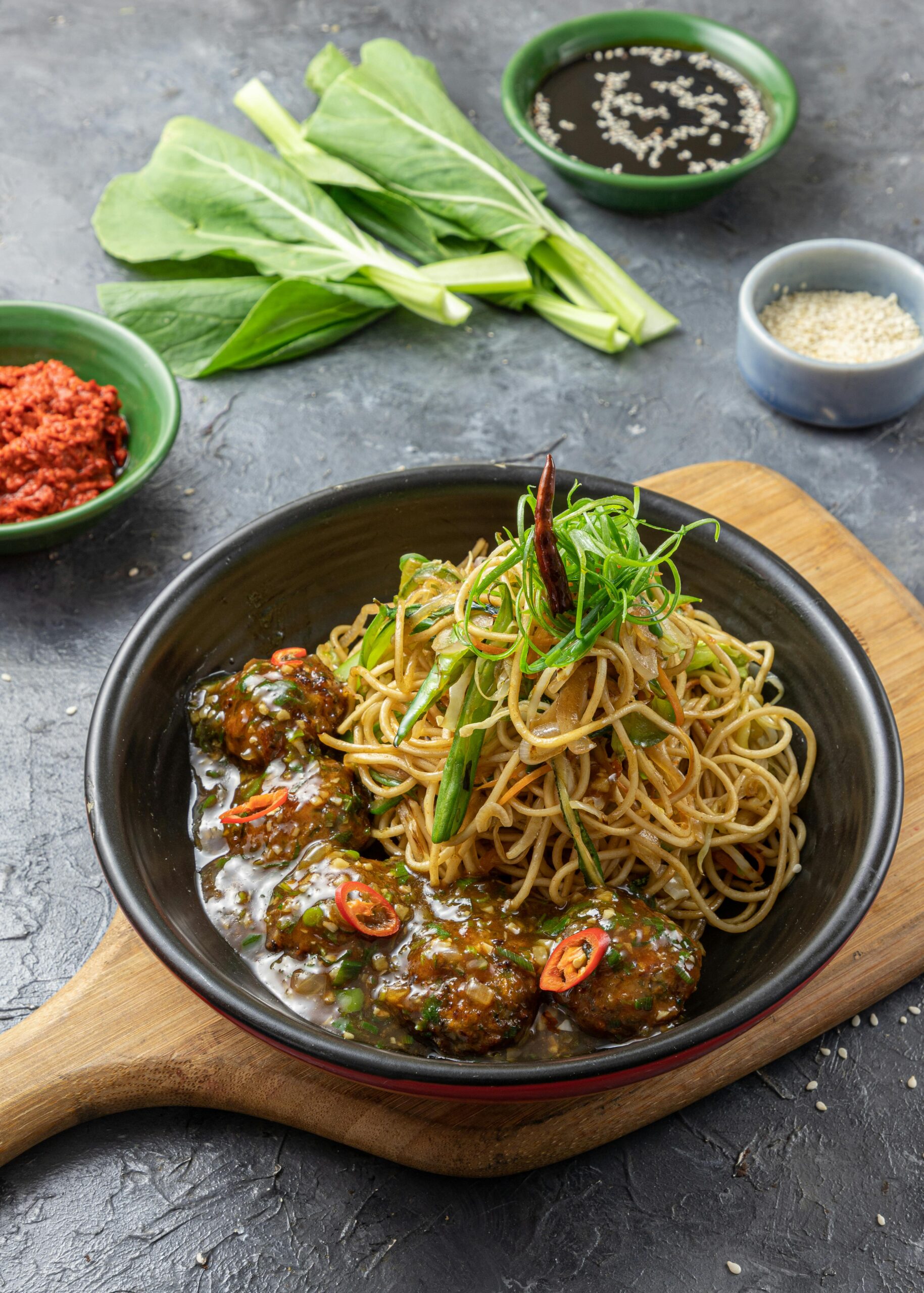 A mouth-watering dish of Asian noodles with savory meatballs, garnished with fresh herbs.