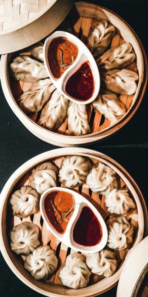 Steamed Nepali dumplings with spicy dips served in bamboo steamers, showcasing cultural cuisine.